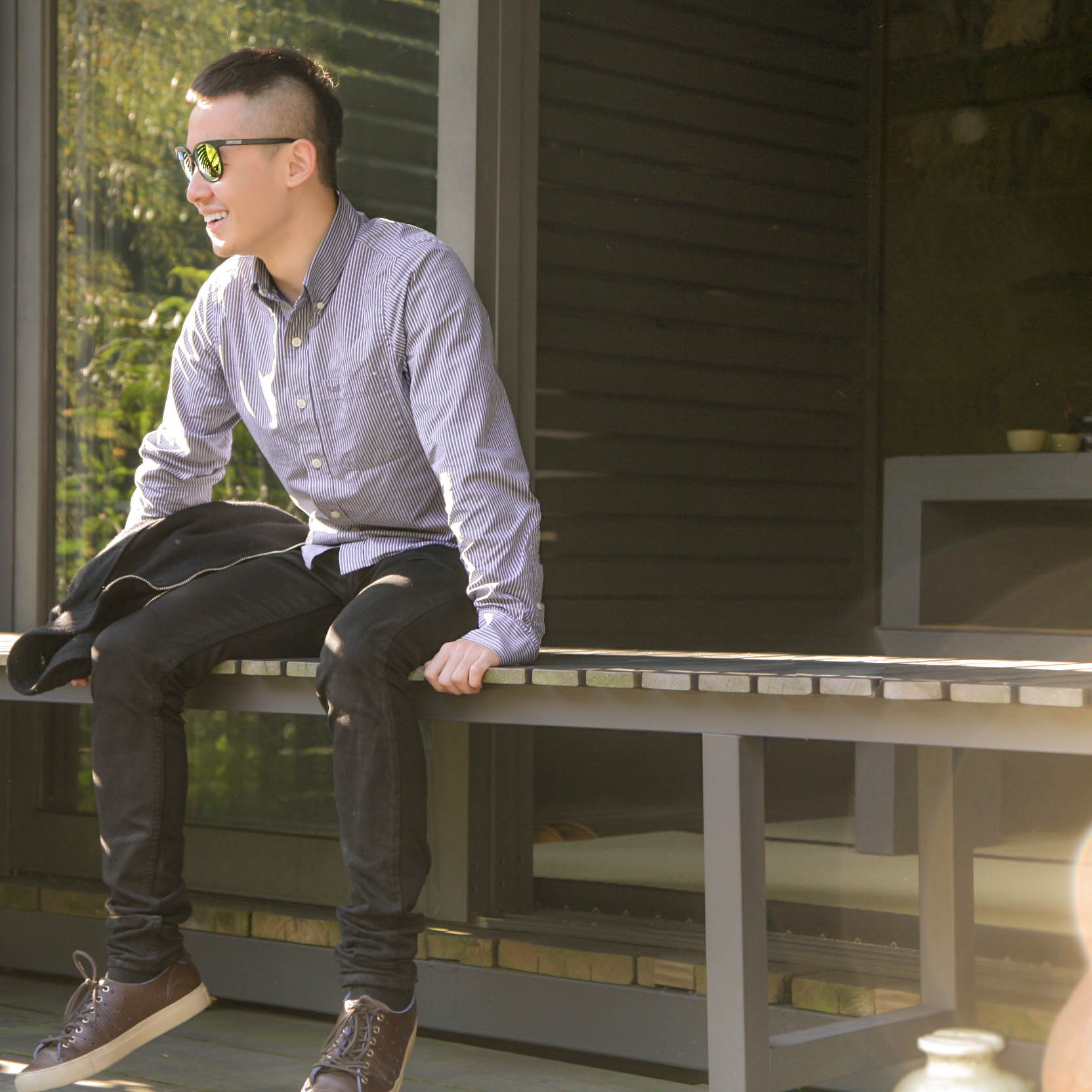 Weinan smiles and looks away from the camera in a sun-filled Japanese garden.